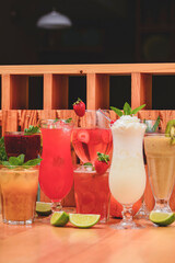 Summer drinks with fruit juice and ice. Refreshing summer beverages in different glasses over rustic wooden background