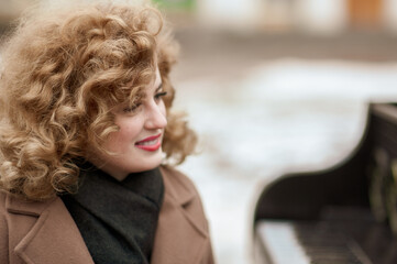 Close-up portrait of a curly-haired girl at the vintage piano on the street