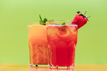 Summer drinks with fruit juice and ice. Refreshing summer beverages in different glasses over green background.