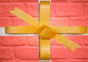 Decorative golden ribbon and bow on a background of red brick wall.