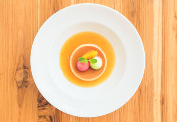 Above view of caramel custard pudding in white plate. Top-down
