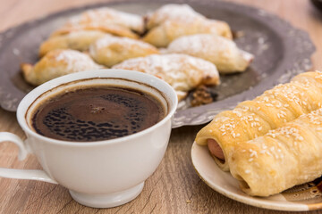  many tasty sausage in bread rolls and cup of coffee for breakfast