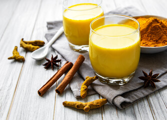 Obraz na płótnie Canvas Yellow turmeric latte drink. Golden milk with cinnamon, turmeric, ginger and honey over white marble background.