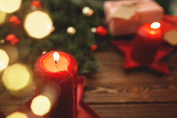 Burning Christmas red candle on brown wooden table