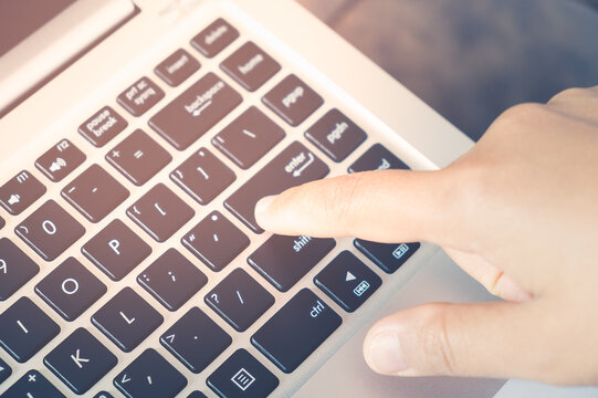 Closeup image of finger pushing button enter provide with data on the laptop computer. Press keyboard on the notebook hardware equipment concept. Top view 