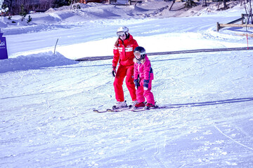 L'Alpe D'Huez, France 02.01.2019 Professional ski instructor is teaching a child to ski on a sunny...