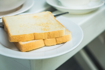 Toast bread in white plate on wooden table at the restaurant.