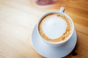 Hot latte art on wooden table at coffee shop.White cup of coffee the best start to any morning at cafe with copy space.