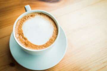 Hot latte art on wooden table at coffee shop.White cup of coffee the best start to any morning at cafe with copy space.