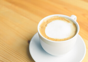 Hot latte art on wooden table at coffee shop.White cup of coffee the best start to any morning at cafe with copy space.