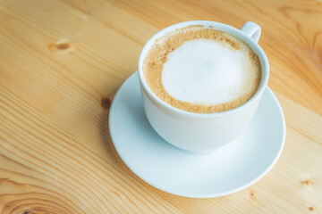 Hot latte art on wooden table at coffee shop.White cup of coffee the best start to any morning at cafe with copy space.