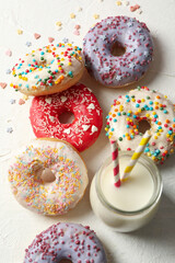 Milk and tasty donuts on white background