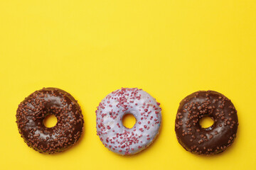 Tasty donuts on yellow background, space for text