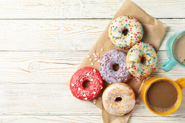 Coffee and tasty donuts on wooden background, top view