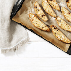 Italian biscotti cookies on black baking sheet. Fresh baked cookies with nuts and dried cranberries.