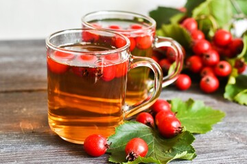 Autumn still life. Cups of tea with hawthorn berries on a wooden table. The background is out of focus. Copy space.
cup of tea