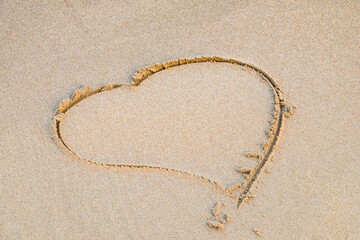 Heart drawn on the beach sand background.