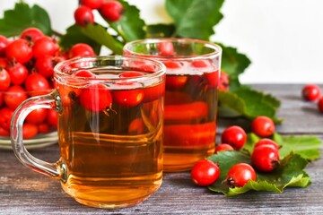 Autumn still life. Cups of tea with hawthorn berries on a wooden table. The background is out of focus. Copy space.

