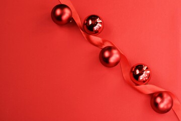 Creative Christmas cards and Happy New Year greeting cards. Red balls and red ribbon on a red background. Flat lay. Copy space.