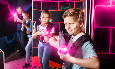 Portrait of teenager boy with laser gun having fun with family on dark lasertag arena