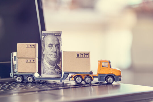 US USD 100 dollar bills, boxes, a trailer truck on a laptop computer, depicts dispatching / delivery goods for online shopping, customers or buyers buy product and service from internet retail store