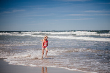 happy child running and jumping in the waves at beach