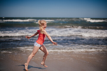 happy child running and jumping in the waves at beach. Reuniting with nature.