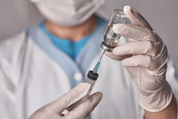 The doctor gets the vaccine into the syringe. Glass bottle in a technician's hand. A bottle with a...