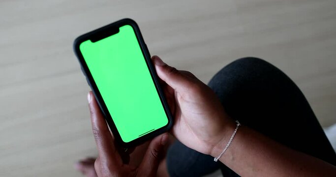 Black woman hands holding cellphone with green screen