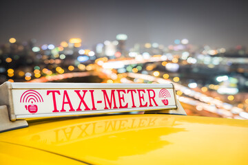 Cropped image of taxi cab roof on busy street at night. Way to travel in the Thailand city.