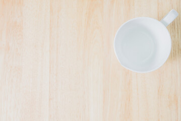 White ceramic mug on rustic wooden table background. View from above. Vintage style