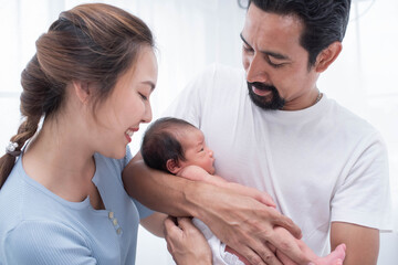 smiling mother and father holding their newborn baby at home..portrait of happy family at home, young parents holding on hands little sweet newborn baby, love and happiness concept.