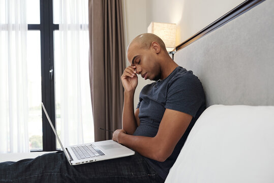 Tired Young Black Man Rubbing Eyes After Coding All Day Long In His Bedroom