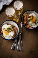 Norddeutscher Hamburger Labskaus mit Rindfleisch Corned Beef, Rote Beete, Kartoffeln, Saure Gurken, Spiegelei, Rollmops und Bier auf Holztisch