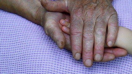 Wrinkled granny hands hold kid hand between. Care concept