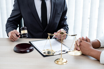 A male lawyer or a judge counseling clients about judicial justice and prosecution with scales, judges gavel, legal documents legal services concept