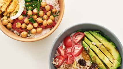 Top view of two bowl with sliced vegetables and rice isolated over white background