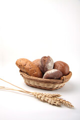 fresh bread in a wicker basket and ears of wheat isolated on white background