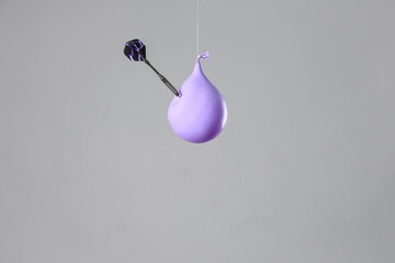 Throwing of dart in balloon with water on grey background