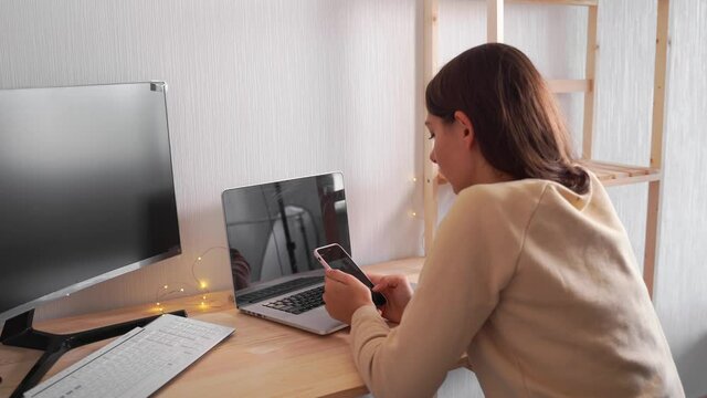 Young caucasian woman scrolling social media while working. Multi screening, procrastination in internet.