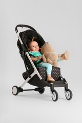 Cute little baby in stroller on light background