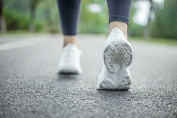Fototapeta na wymiar Runner feet running on road closeup on shoe. woman fitness sunrise jog workout welness concept.
