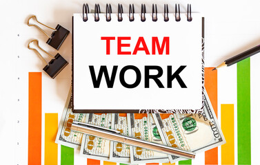 Inscription TEAM WORK in notebook, concept of planning, with office tools ,chart and dollars