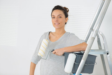 beautiful young slim builder girl holding paint roller