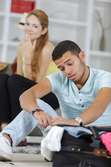 Fototapeta premium young man struggling while packing suitcase