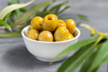 Pitted green olives in white plate with green leaves