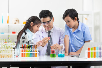 science teacher doing or testing a chemical experiment with child students in laboratory classroom