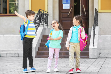 Happy little pupils near school outdoors