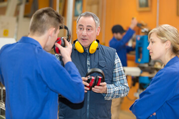 industrial apprentice putting earmuffs on