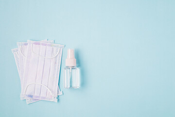 Hygiene face mask and alcohol gel on blue background for healthcare and sanitary items concept